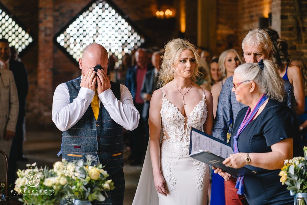 Wedding Photography at Shustoke Barn of emotional groom during ceremony seeing his wife to be for the first time in the dress