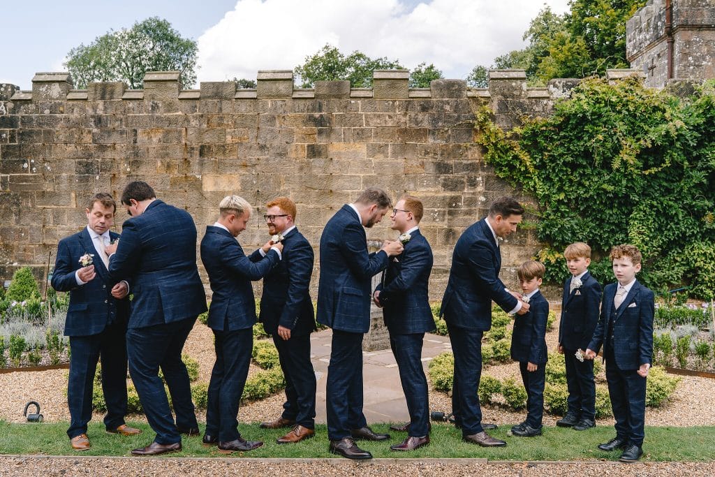 Photo of groom and groomsmen putting on buttonholes at wedding at Wadhurst Castle by Wadhurst Castle wedding photographer, Parkershots